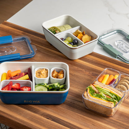 Bento boxes with compartments containing various food items on a wooden table.
